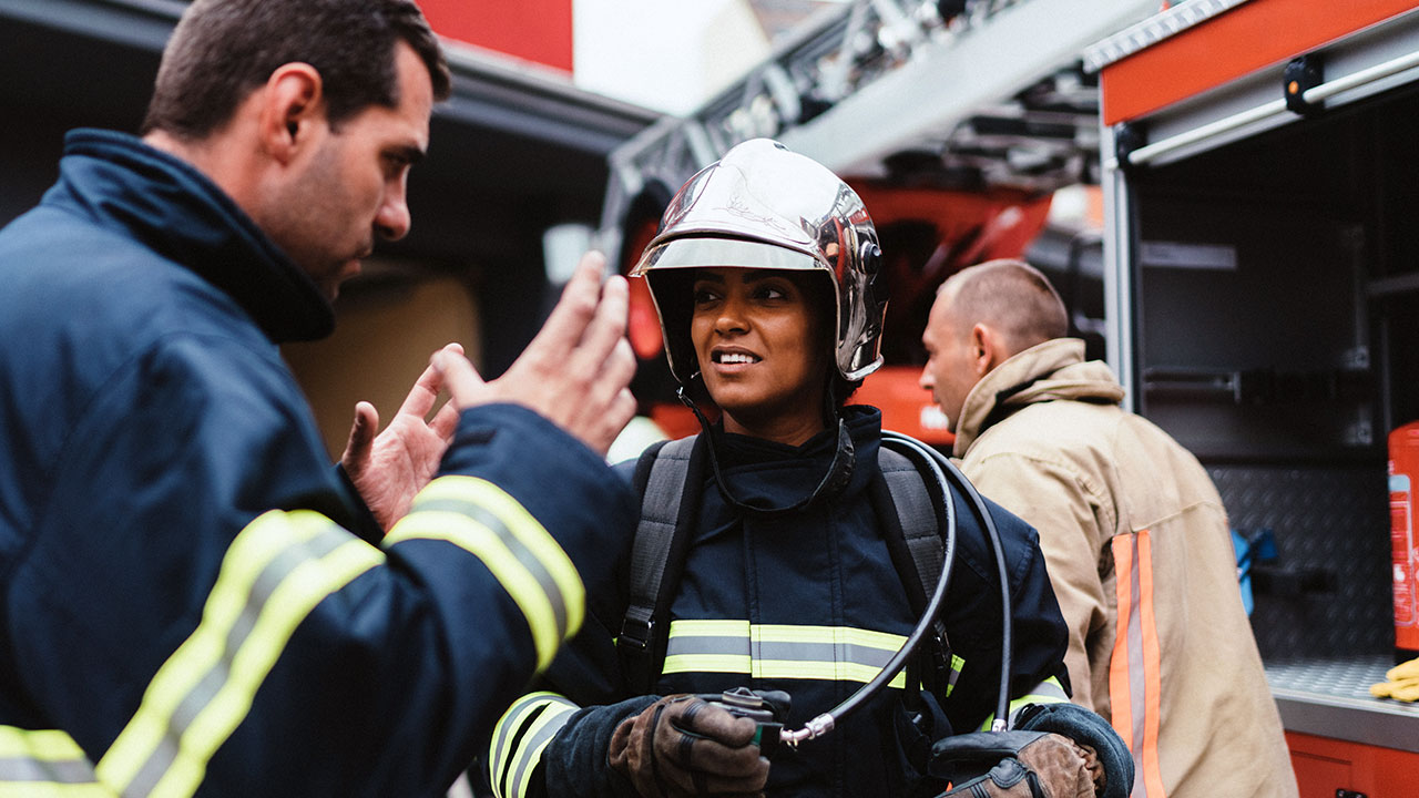 A trainer gives instruction to a firefighter during a disaster drill
