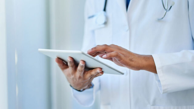 A medical professional holding a tablet in a hospital. Tetra Tech helps health care stakeholders protect data