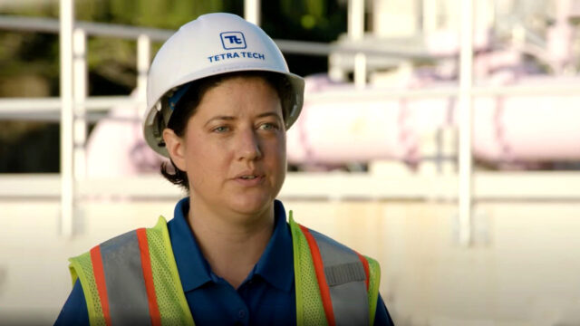 A video screenshot of a Tetra Tech employee in a safety vest and hard hat