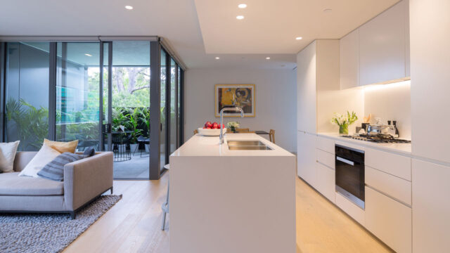A kitchen area in a residential apartment with a terrace area beyond a sliding glass door