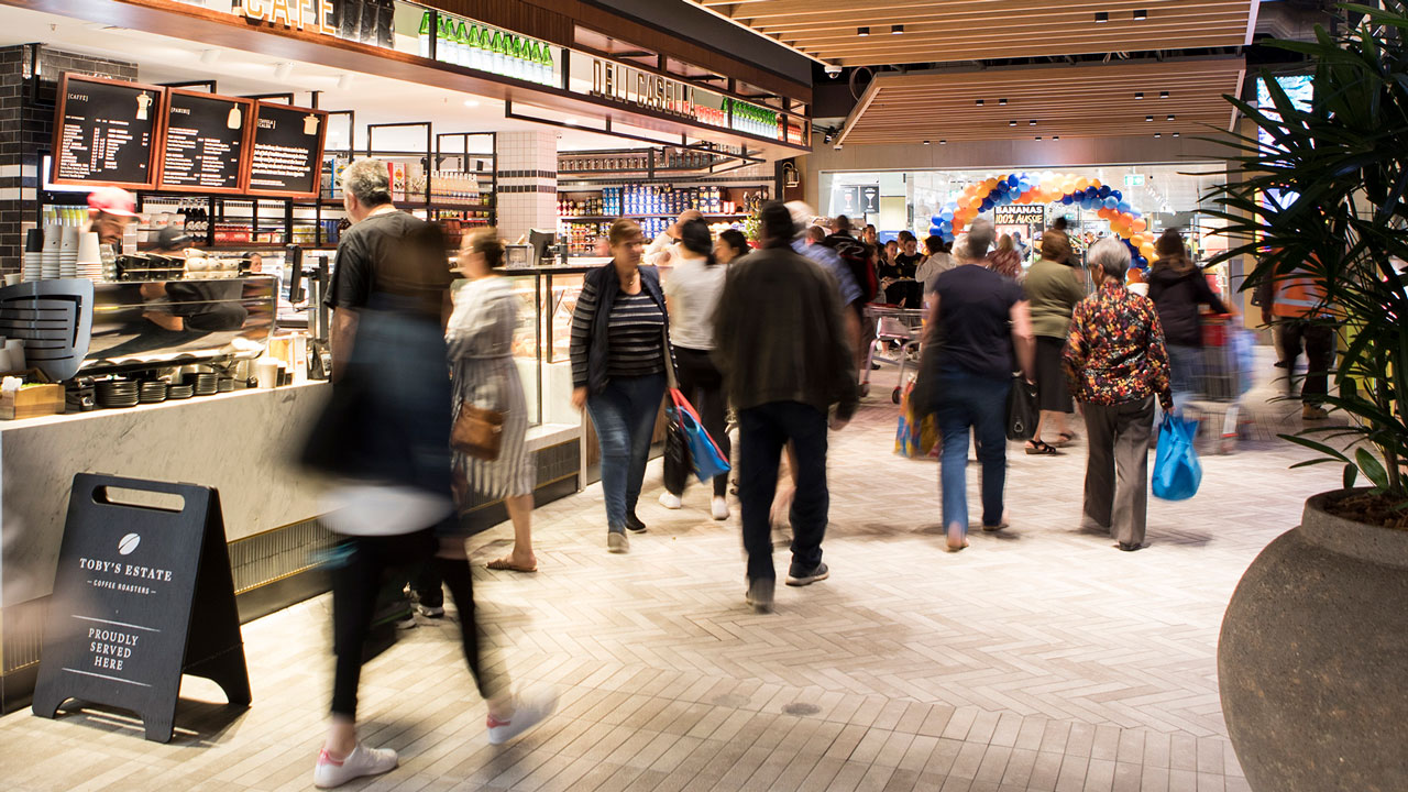 A busy retail food hall with people actively ordering and walking by