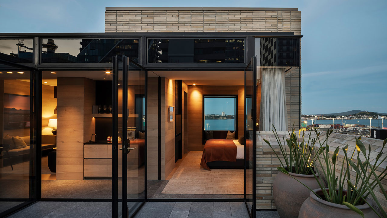 A hotel room at Hotel Britomart with floor-to-ceiling glass doors open to a rooftop outdoor space