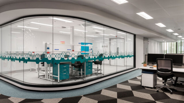 A small lab space within an office floor. The lab space is separated by a curved glass wall