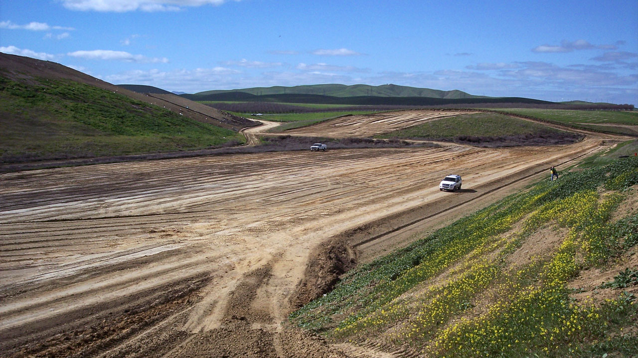 An SUV being driven on a dirt road of a landfill expansion