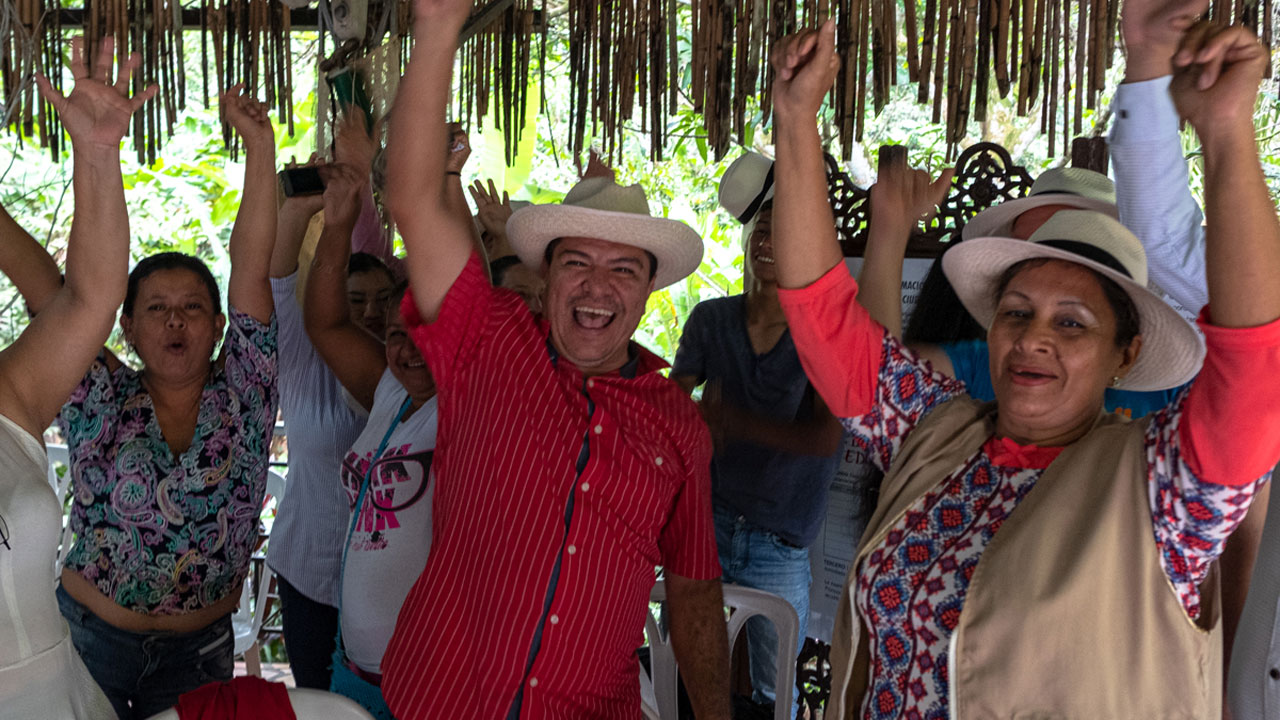 A group of people in Colombia stand together raising their arms and smiling