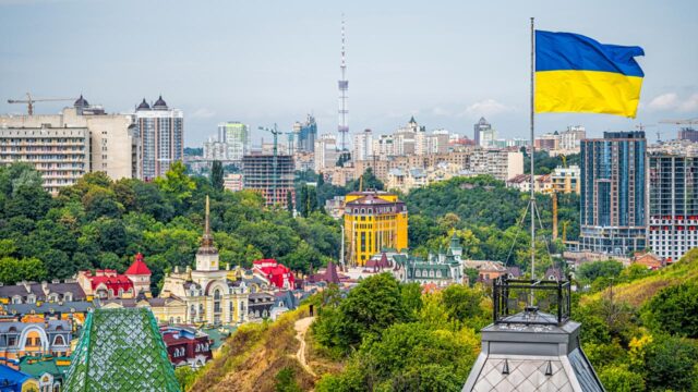 Kyiv, Ukraine cityscape of Kiev and Ukrainian flag waving in the wind during summer in Podil district and new buildings