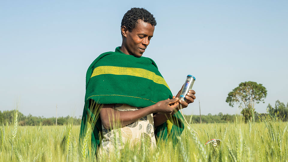 Man holding a water saving tool, part of BIFAD’s importance of agricultural research to generate innovations