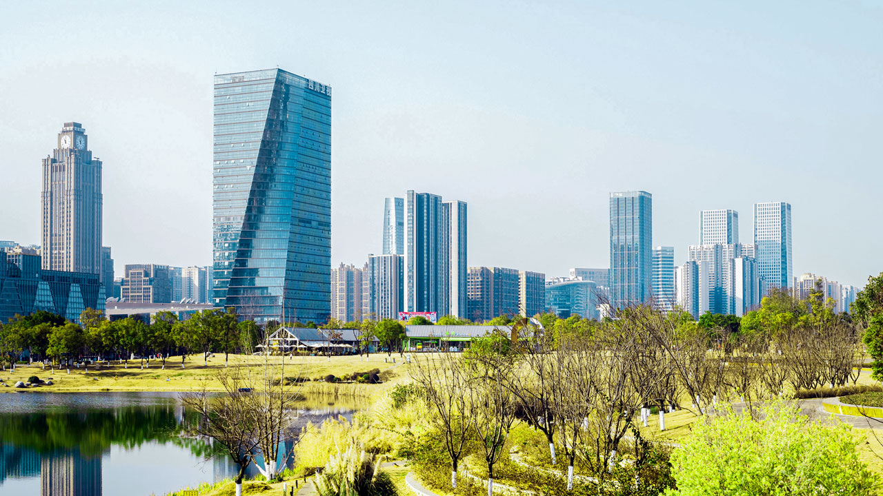 A park and waterbody with a city skyline in the background