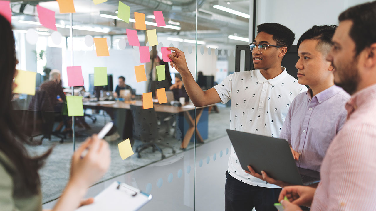 Business people strategizing a mobile app with sticky notes on a glass wall