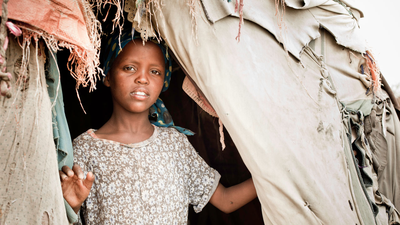 Young Somali girl looks out from her hut at an IDP camp