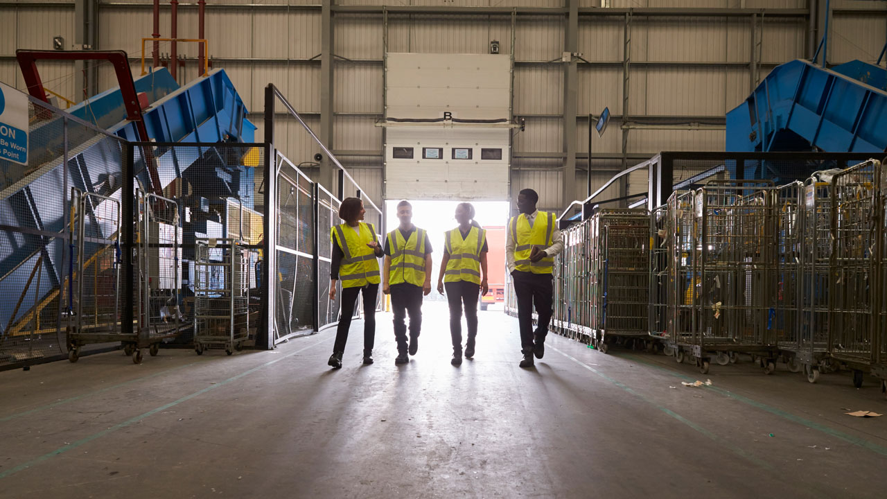 Four employees on the floor of the transferring station reviewing equipment set up