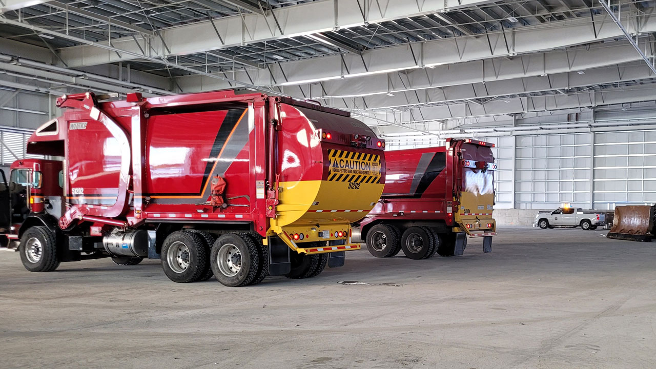 Two garbage trucks inside a transfer station facility