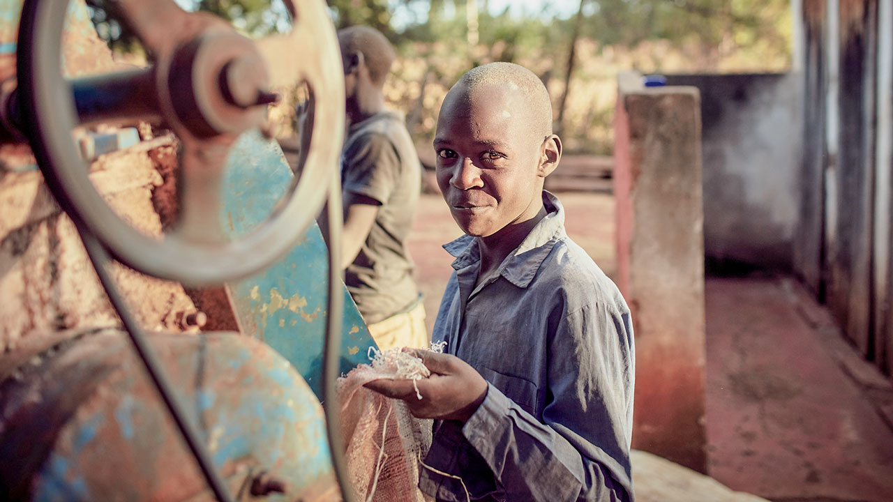 Young man smiles at camera holding grain in his hand