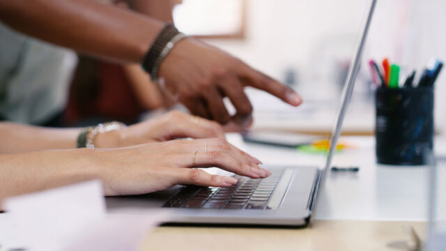 Closeup of hands working at a laptop on a desk