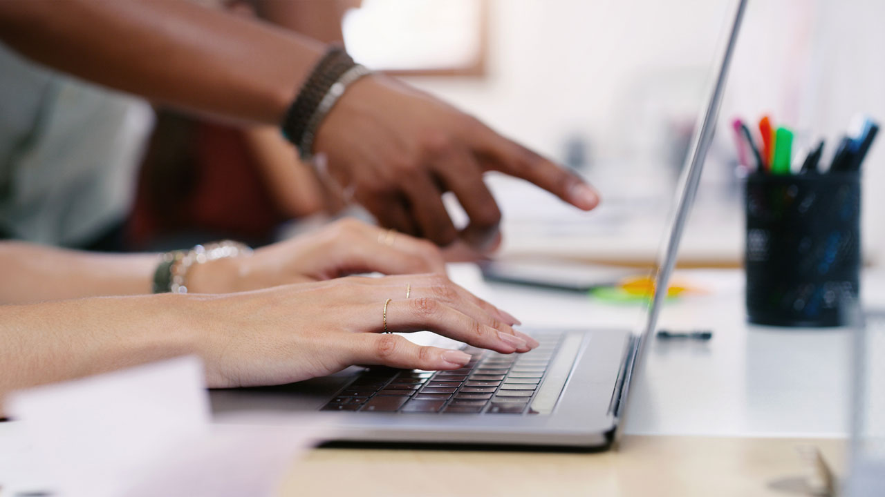 Closeup of hands working at a laptop on a desk
