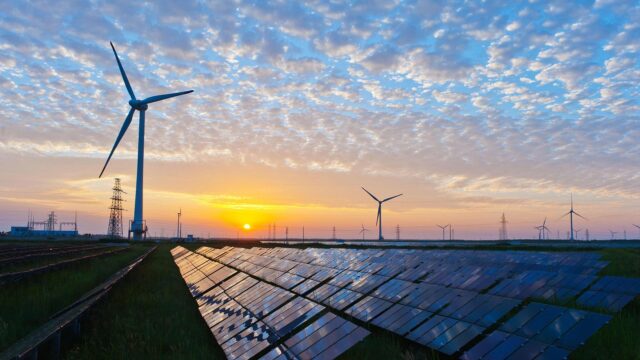 Solar panels and wind turbines at sunset