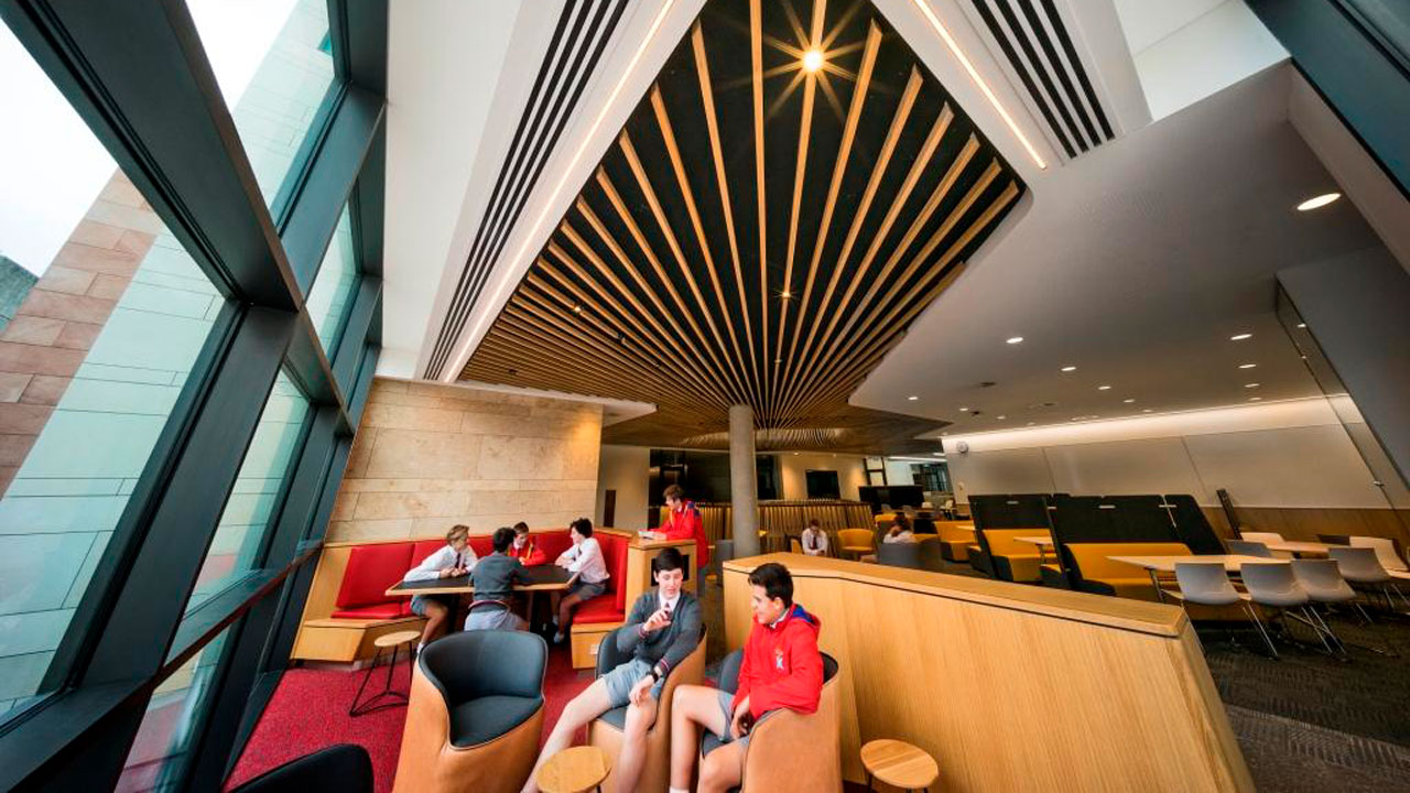 Students sitting together on tub chairs within an architectural school space