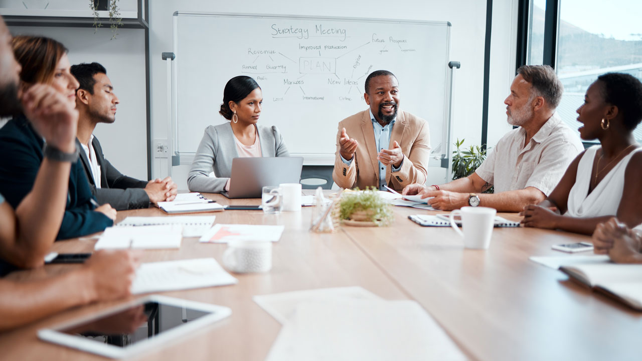 Team members around a conference table discuss projects