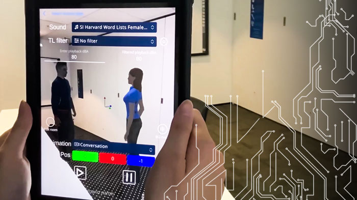A view of a room and hands holding an iPad displaying the AiHear app with a projection of sound changes to the space