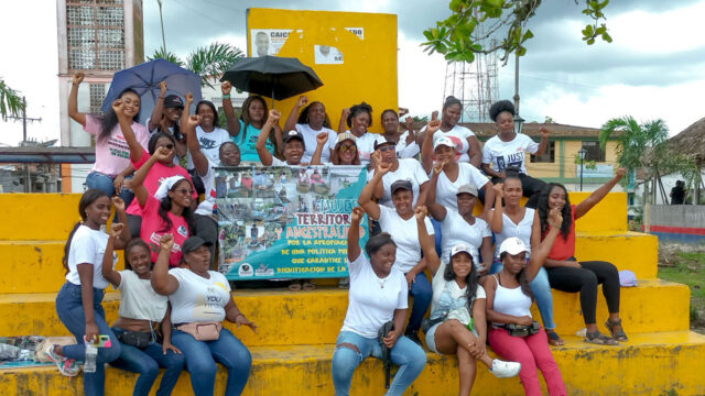 Group of people with their arms raised at a community activity in Colombia