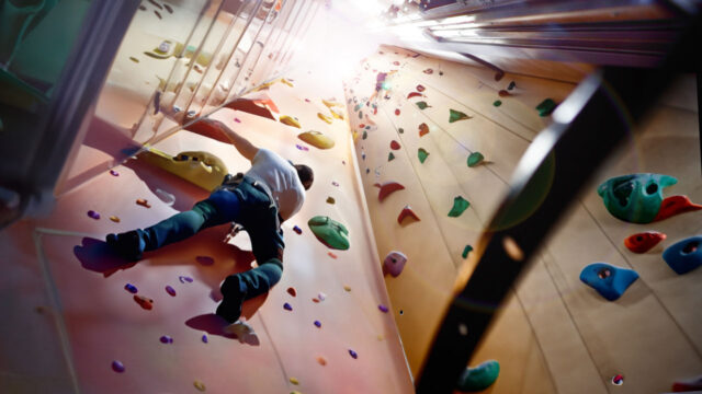 A rock climber going up a rock-climbing wall repurposed from an empty elevator shaft