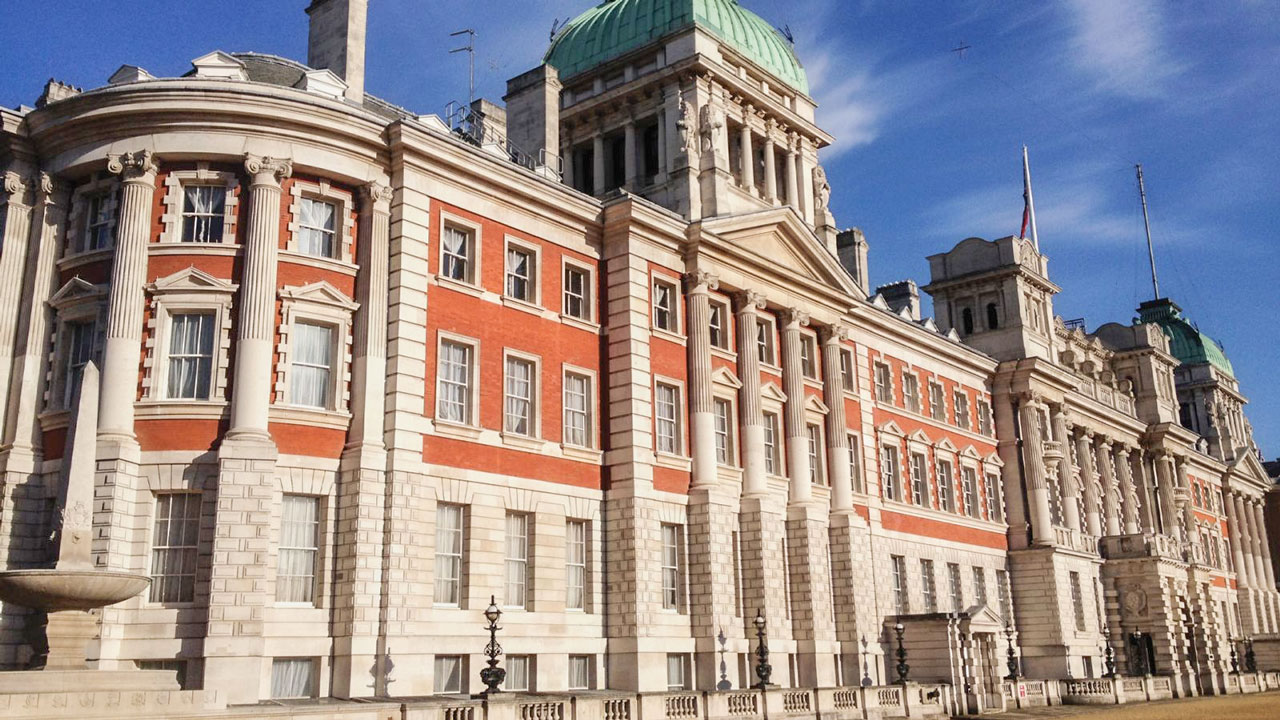 Large multi-story government building featuring gray and red bricks and multiple columns