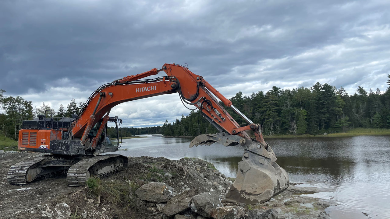 An excavator in front of a body of water at a project site
