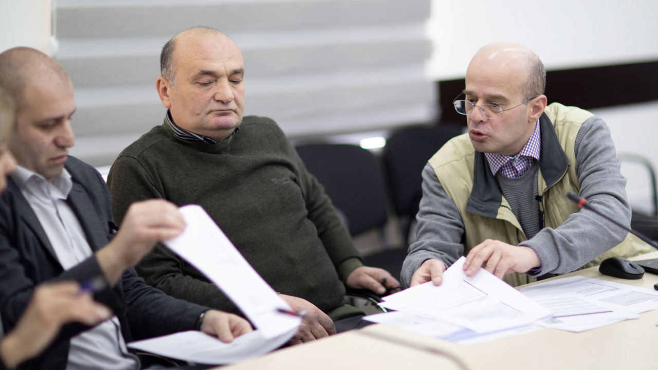 Three people sitting at a table looking at documents