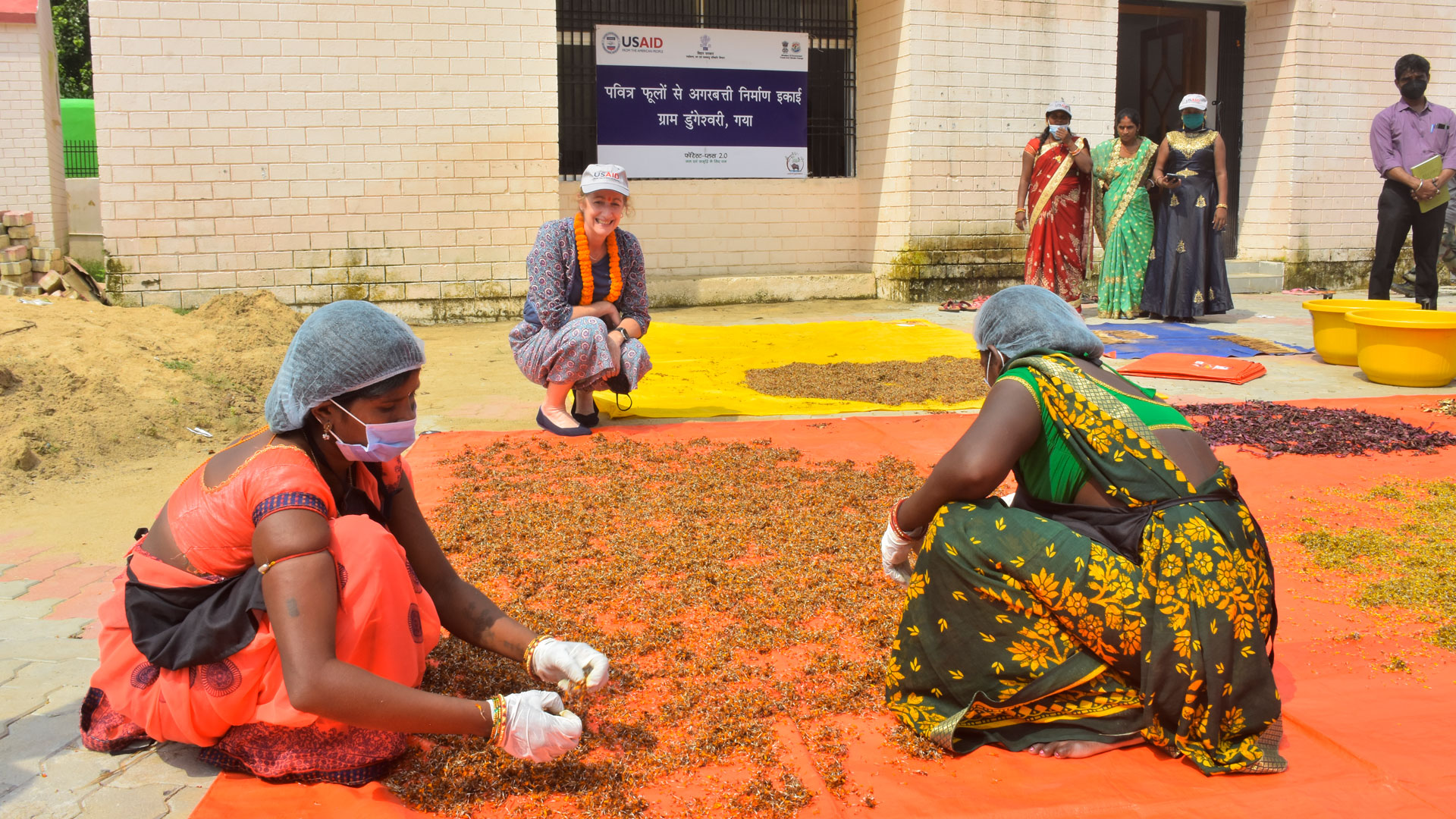 Women kneeling and collecting flowers to recycle as part of a women-led eco-products manufacturing unit set up by Tetra Tech’s Forest-PLUS 2.0