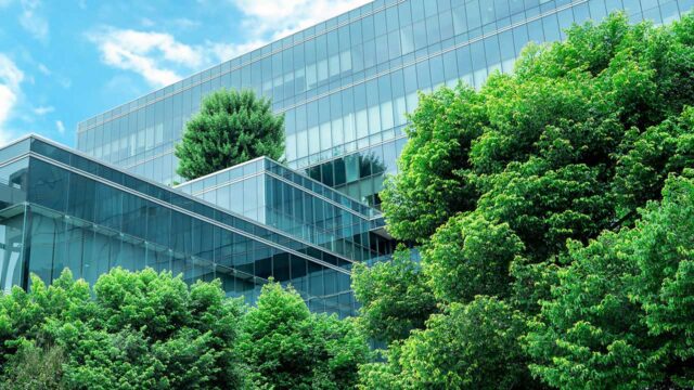 Low angle view of glass building surrounded by trees