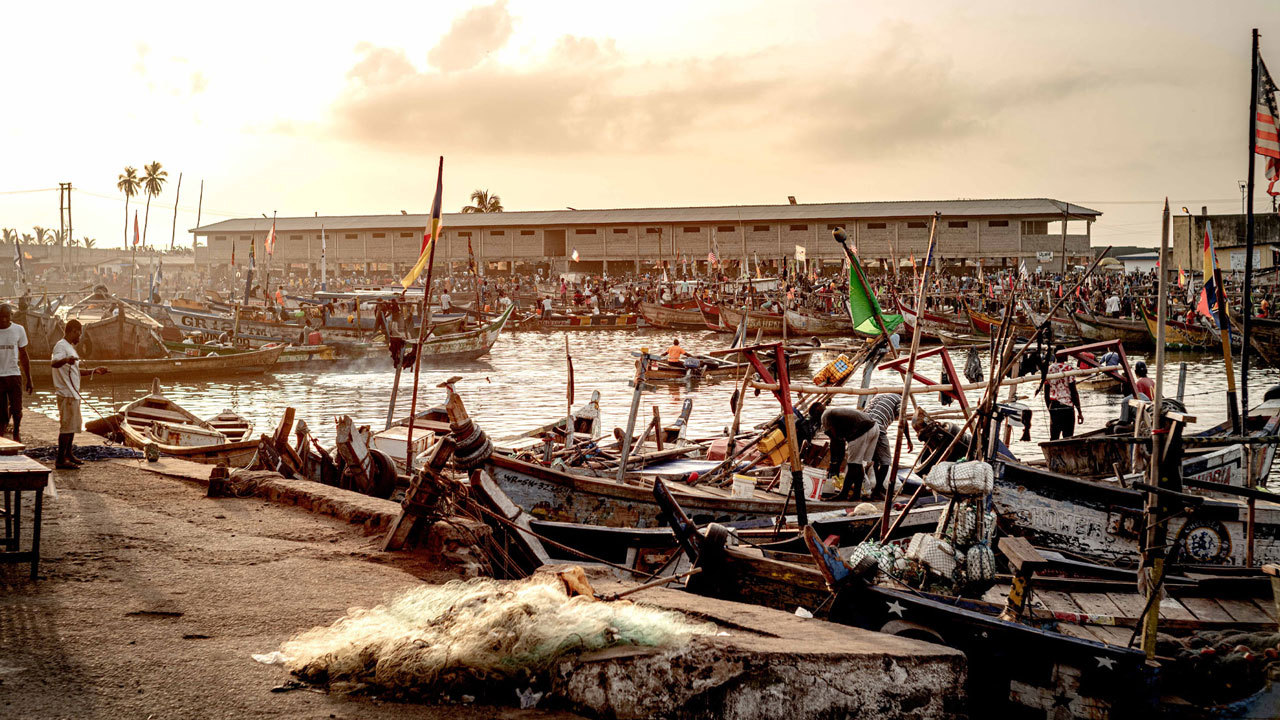 View of coastline in Ghana with small, pelagic fishing boats docked on the sand