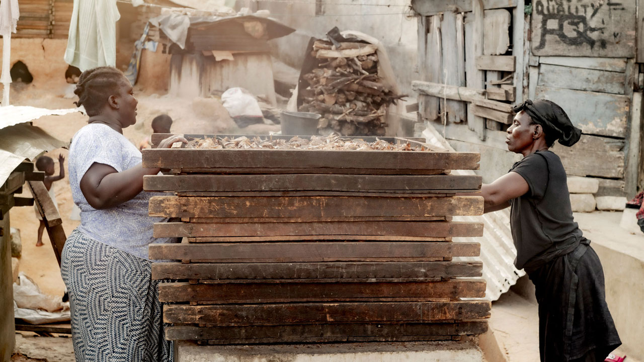 Two women working at a fish smoker