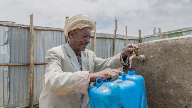 A man fills a water can at a water collection point in Ethiopia