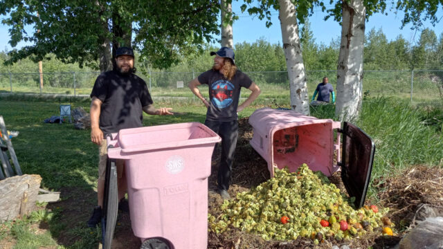 Two community members standing in front of two waste bins