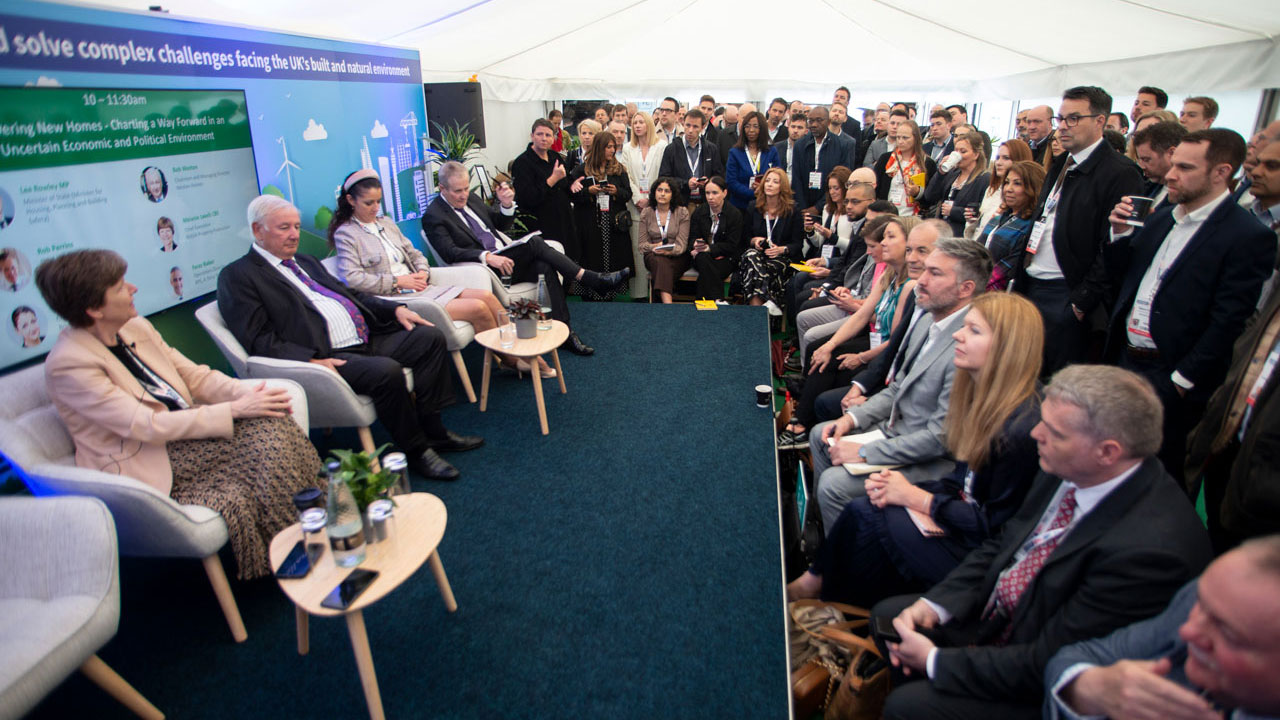 Group of people in the audience watching a panel discussion on a stage