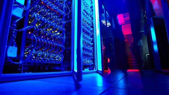 Banks of servers in a data center lit with blue lights