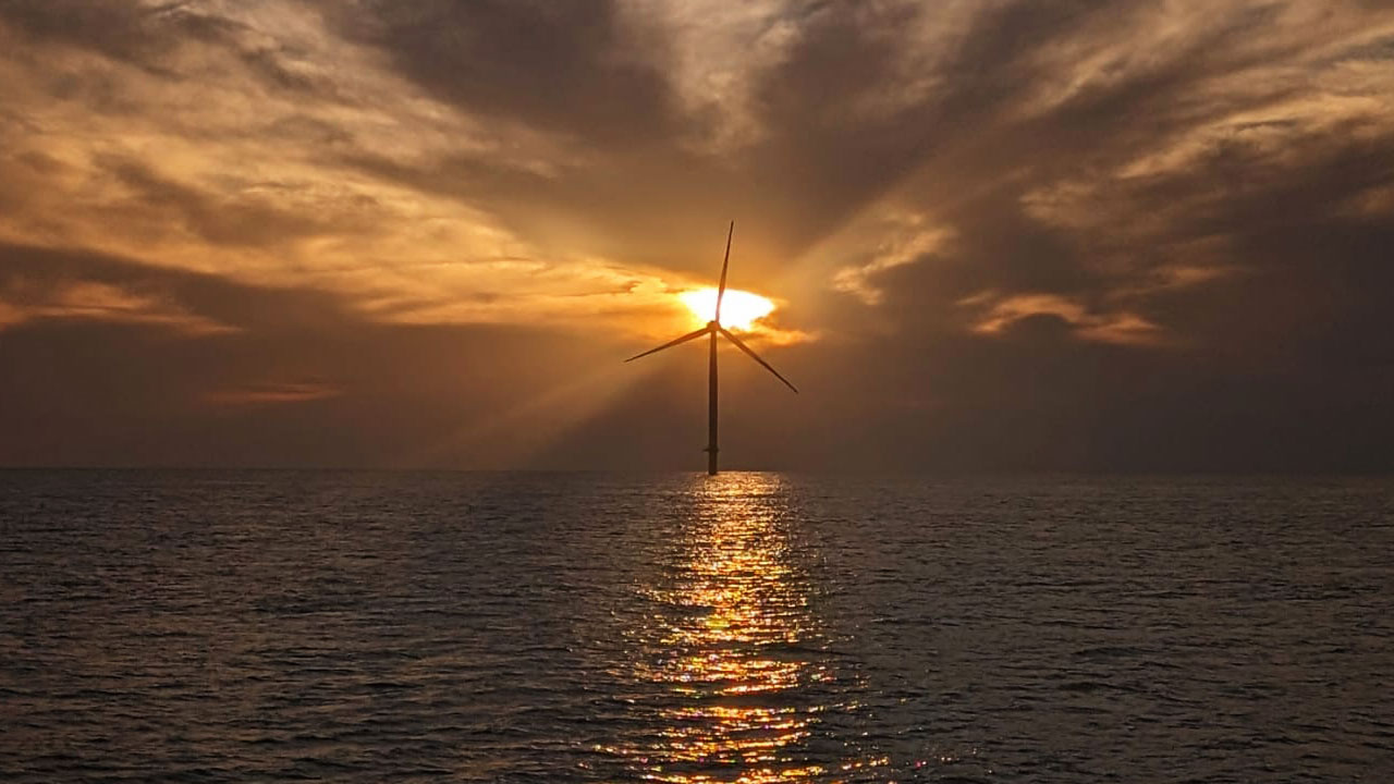 Offshore wind turbine with a service vessel nearby on calm ocean waters