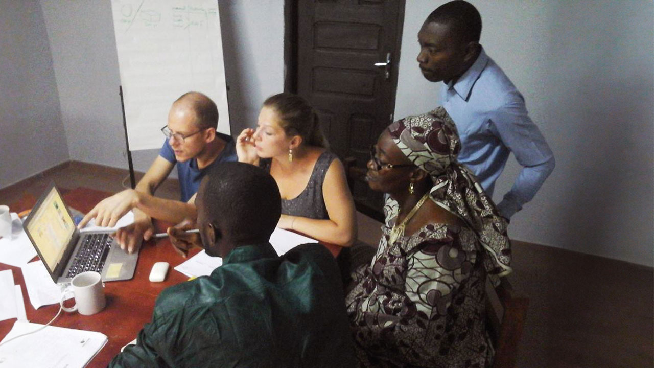Six people gather around a laptop