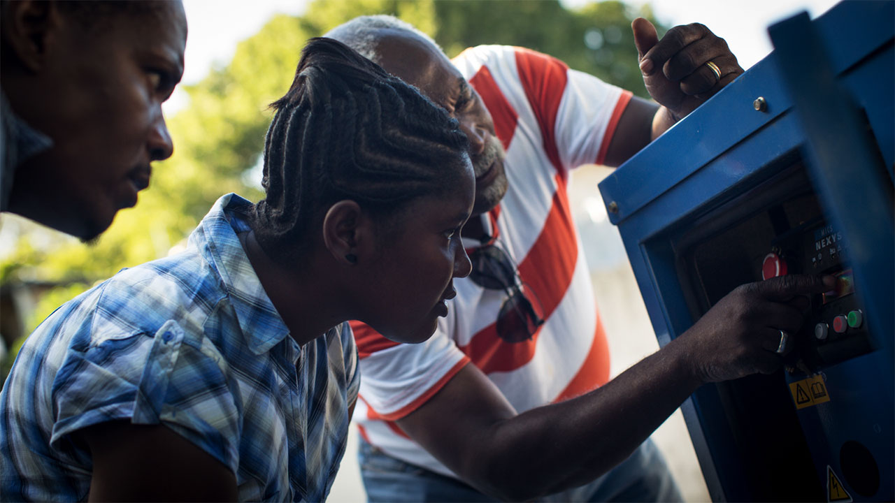 Three people looking closely at an electricity control box