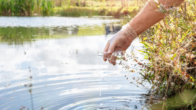 Person testing water with a glass beaker