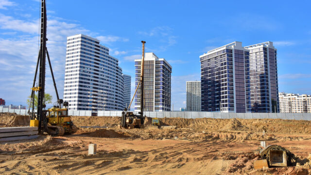 View of a building site with equipment in the foreground and small skyscraper buildings in the background
