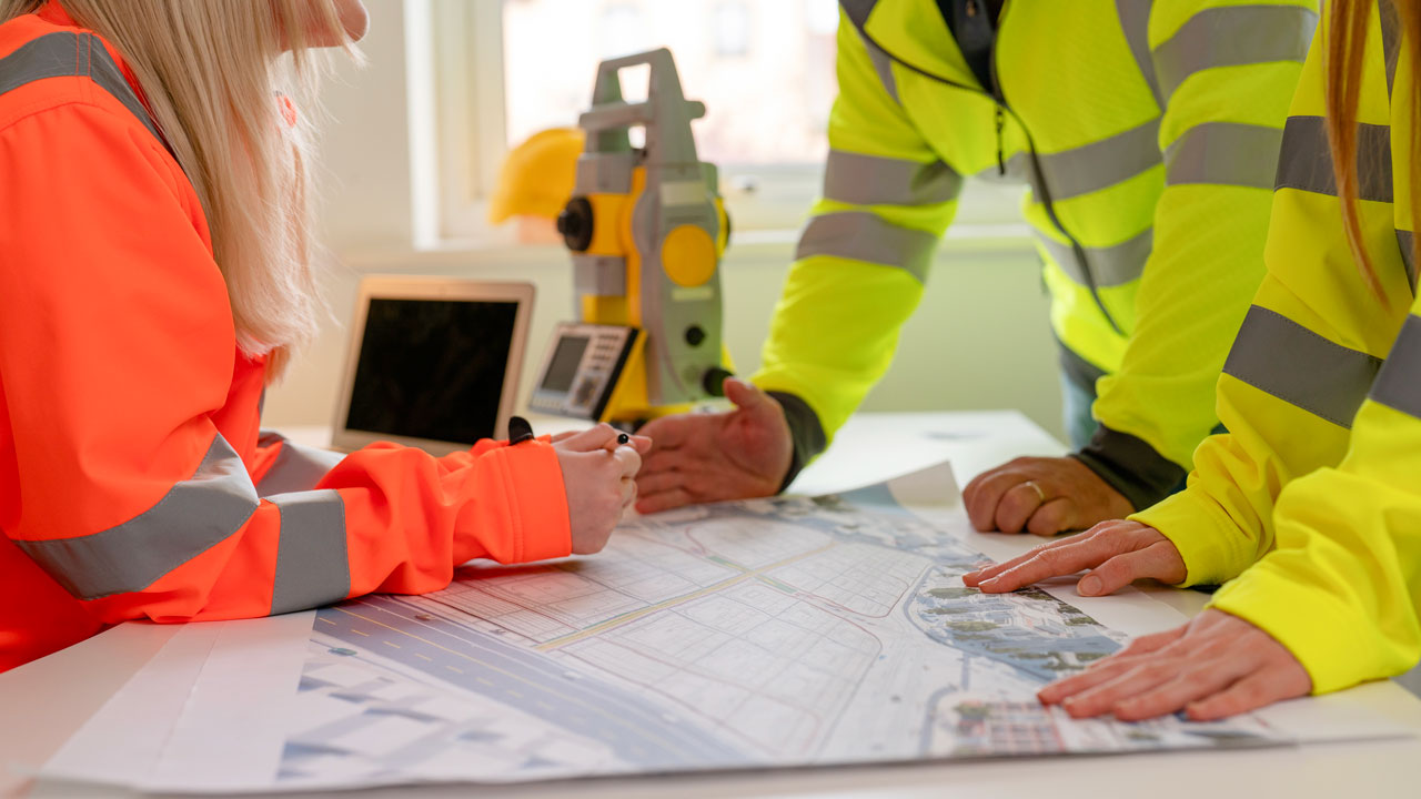 A group of engineers in high-vis workwear review a site plan 