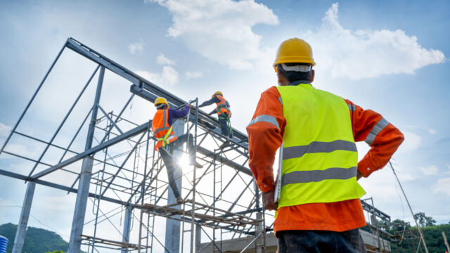 Man in high-vis vest looks on as another person surveys infrastructure