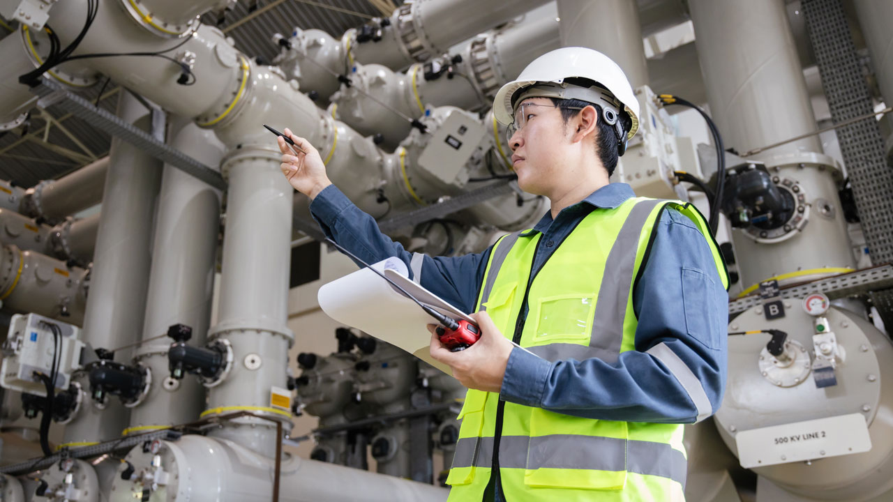 Engineer in personal protective equipment inspects piping for safety 