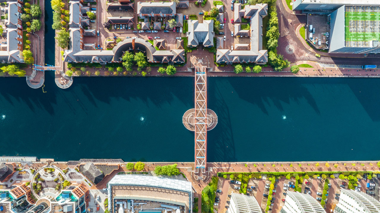 Drone view of Manchester city with a river running through the middle of the photo and buildings on either side of the water