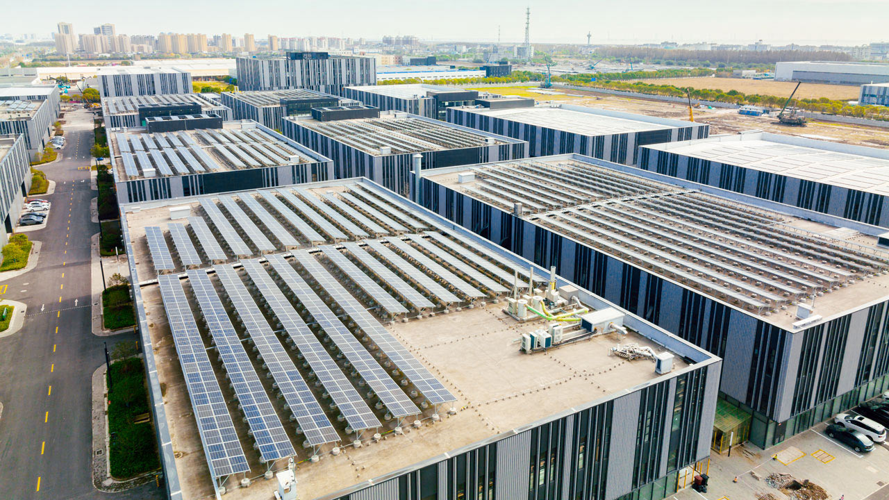 Aerial view of buildings with solar panels on top and a city skyline in the distant background