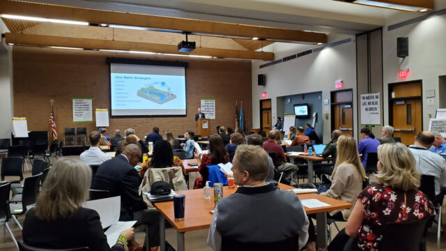 Audience seated at a stakeholder engagement meeting watching a presentation on One Water Strategies