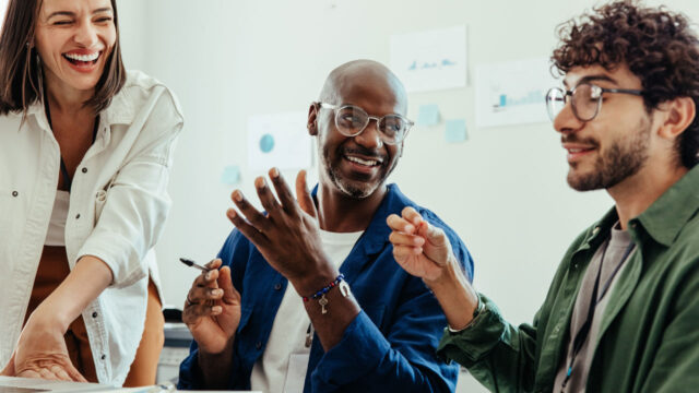 Three people sitting at a table smiling and in conversation