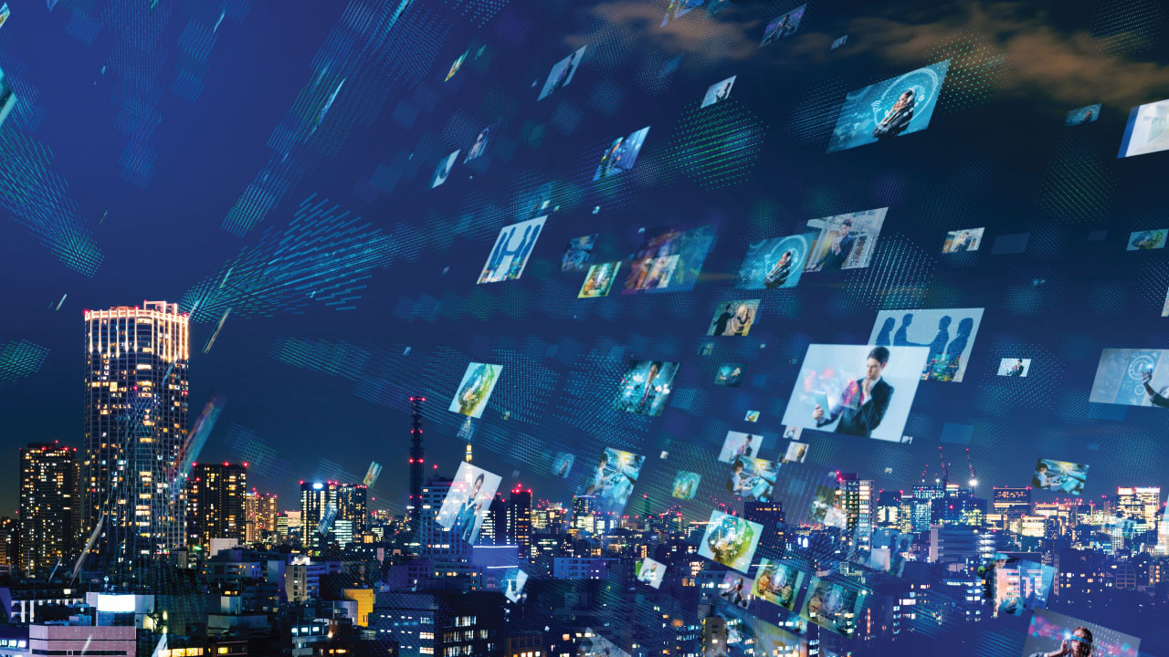 City skyline at night with an overlay of various images being projected from a tall building