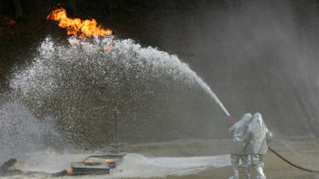 Image of firefighters spraying foam at a burning building